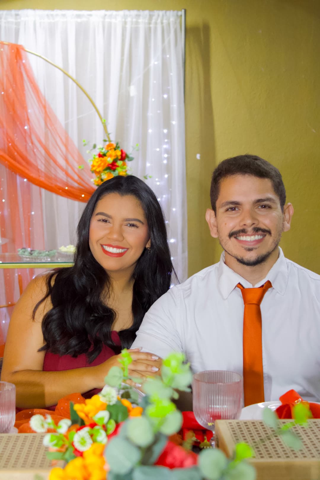 O casal sorrindo à mesa decorada