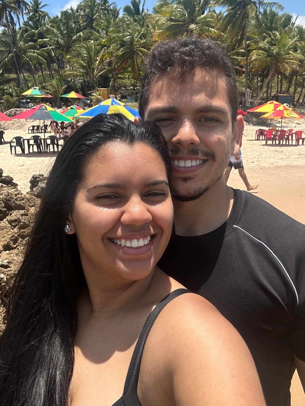 O casal na praia entre coqueiros