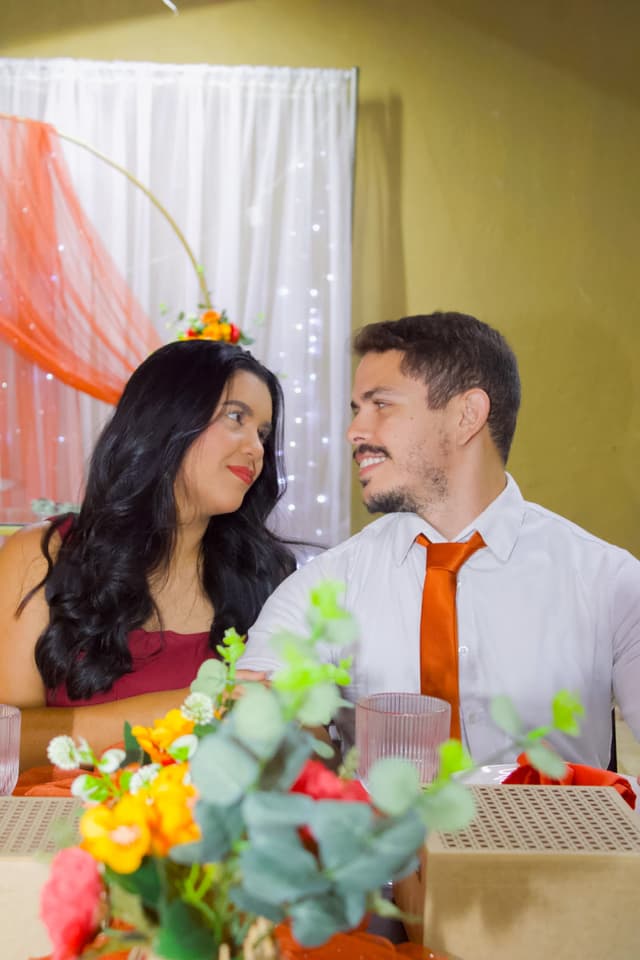 O casal sorrindo um para o outro à mesa